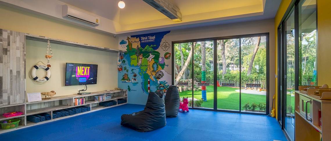 Ein Kinderzimmer im Dusit Thani Krabi Beach Resort mit bunten Wänden, einer Fernsehwand und einer Aussicht auf den Garten.