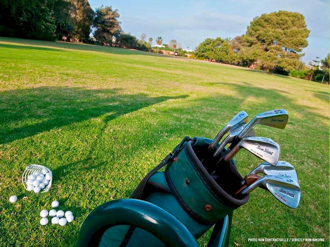 Golfplatz mit einem Golfbag, Schlägern und Bällen auf dem Rasen.