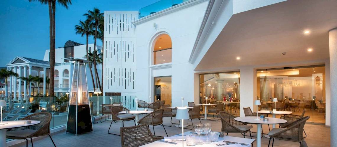 Terrasse des Guayarmina Princess Hotels mit Tischen, Stühlen und Palmen im Hintergrund