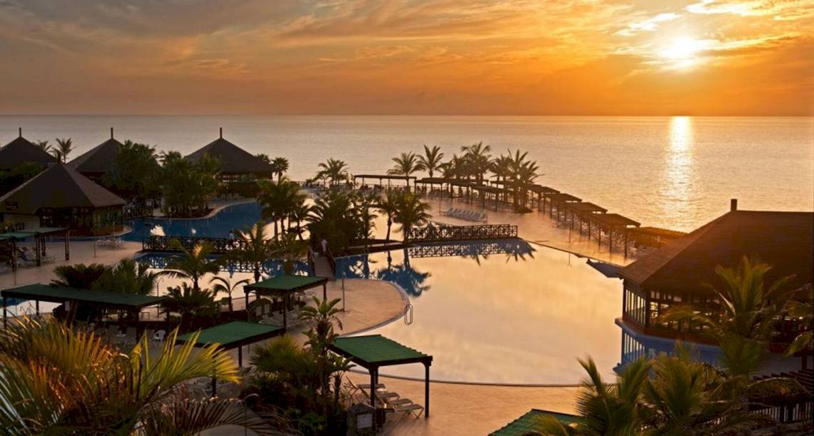 Guyarmimina Princess Hotel mit Pool und Meerblick bei Sonnenuntergang.