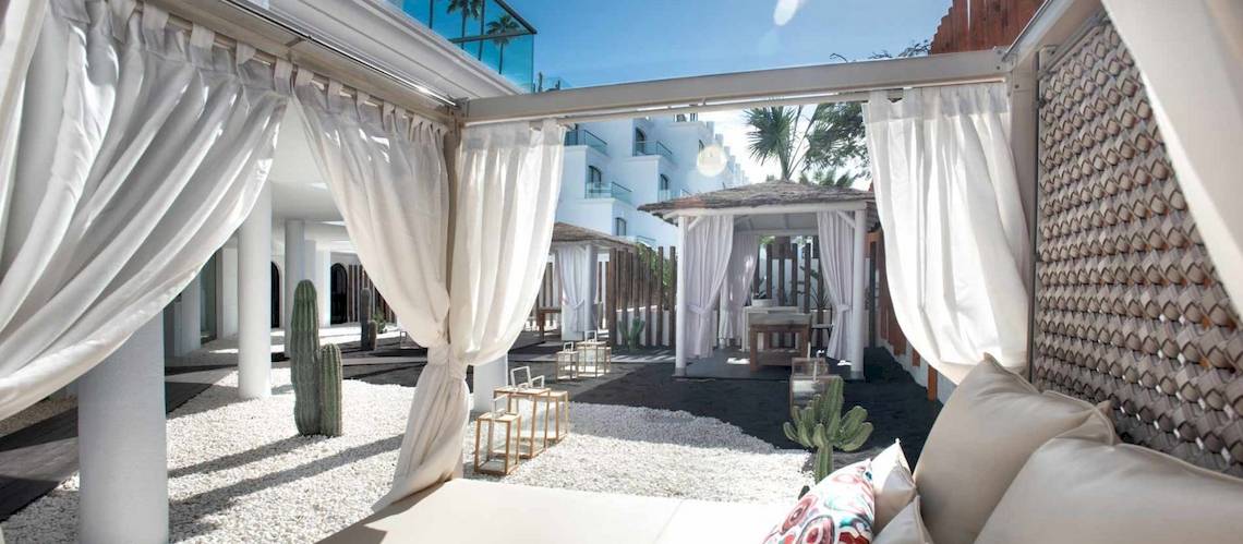 Außenbereich des Guayarmina Princess Hotels mit weißen Vorhängen und weichen Kissen.