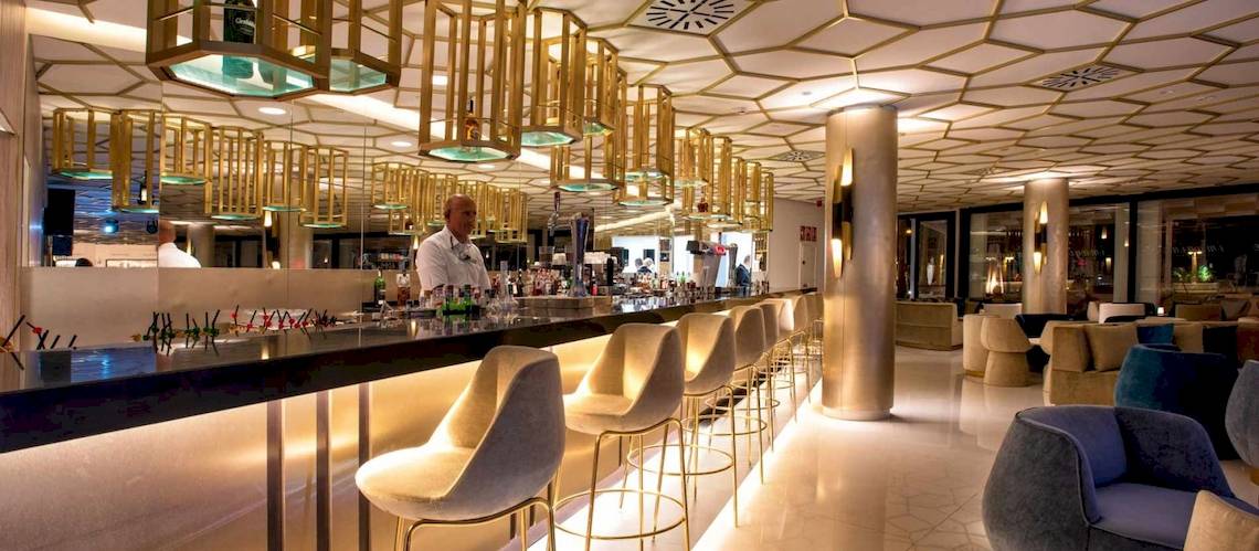 Innenansicht der Bar im Guayarmina Princess Hotel mit goldenen Kronleuchtern und modernen Stühlen.