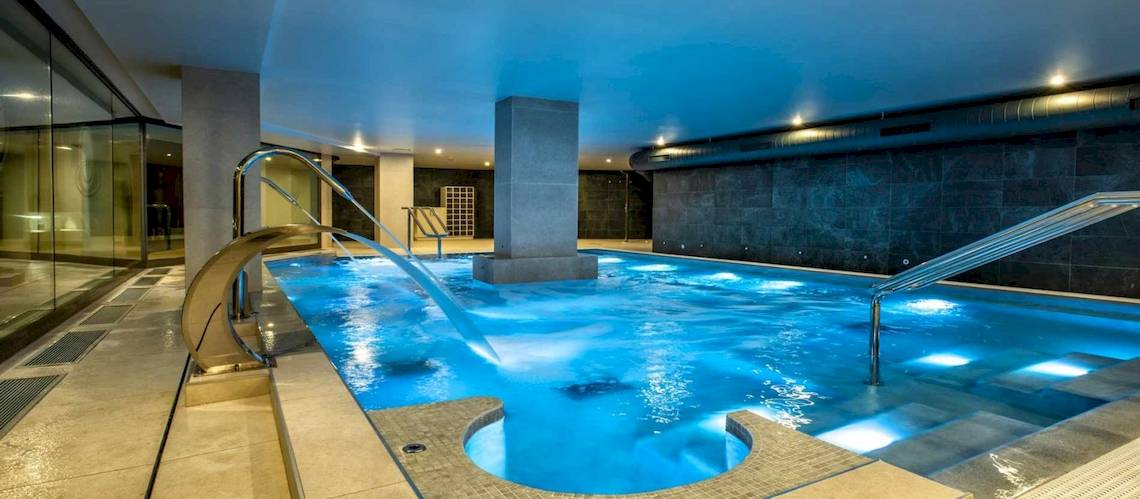 Innenpool des Guayarmina Princess Hotels mit blauem Wasser und beleuchteten Stufen.
