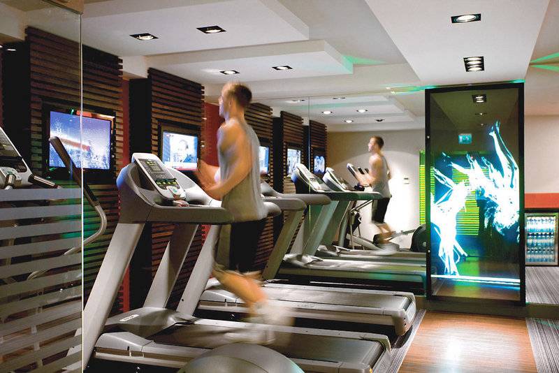 Fitnessstudio im Clermont Hotel mit Läufern auf Laufbändern und Fernsehern an der Wand.