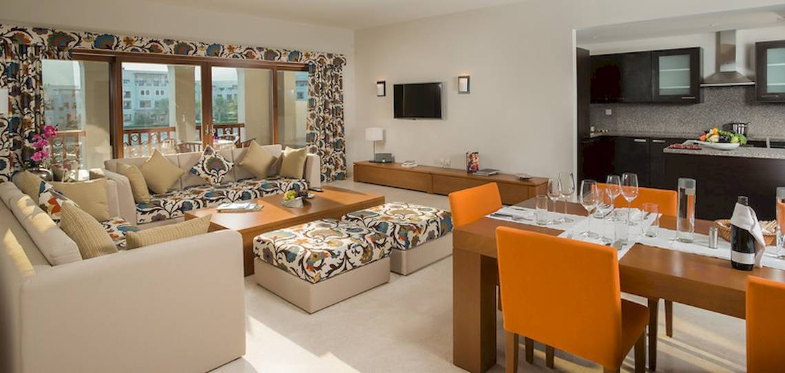Das Wohnzimmer des Sifawy Boutique Hotels mit Couch, Esstisch und Fernseher.