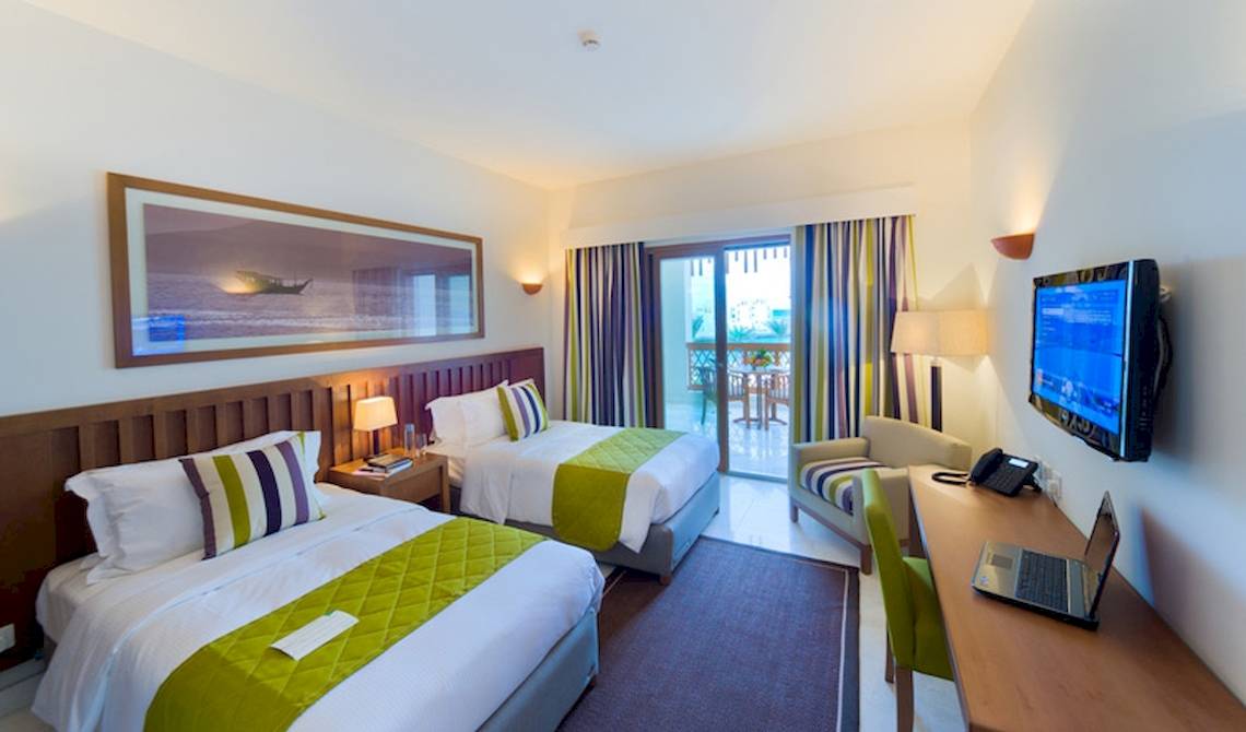Doppelzimmer im Sifawy Boutique Hotel mit zwei Betten, Fernseher, Schreibtisch und Balkon.