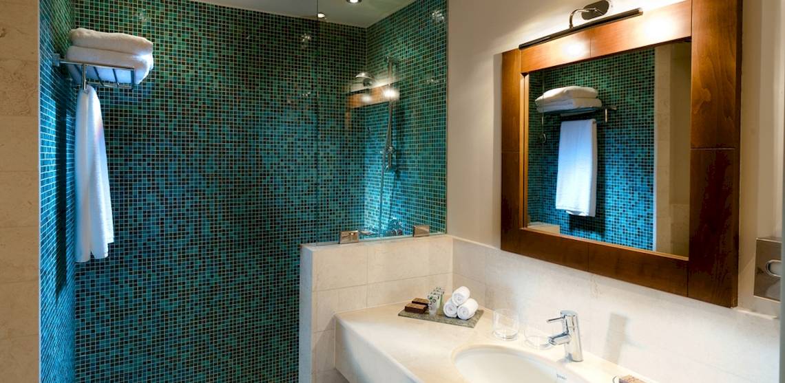 Badezimmer im Sifawy Boutique Hotel mit blauen Fliesen und einem großen Spiegel.