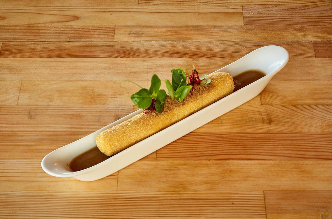 Gebäck in einer weißen Schüssel mit Sauce auf einem Holztisch