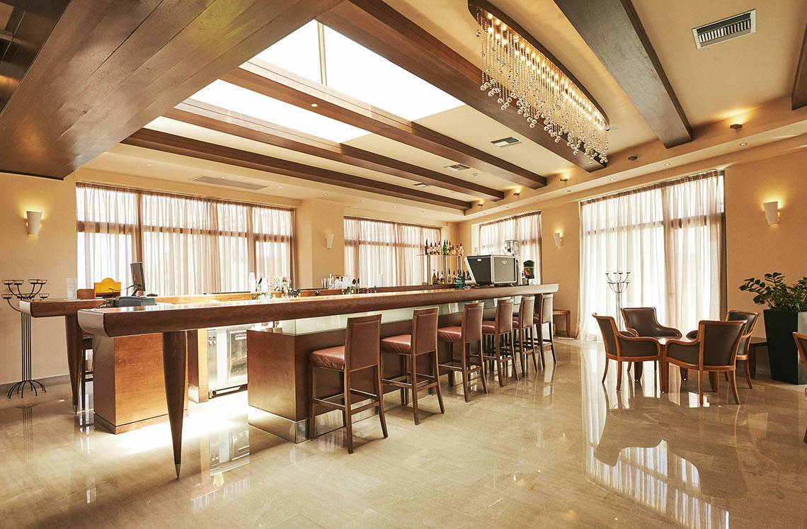Bar im Giannoulis Cavo Spada Sports & Leisure Resort mit Theke, Stühlen und Tisch.