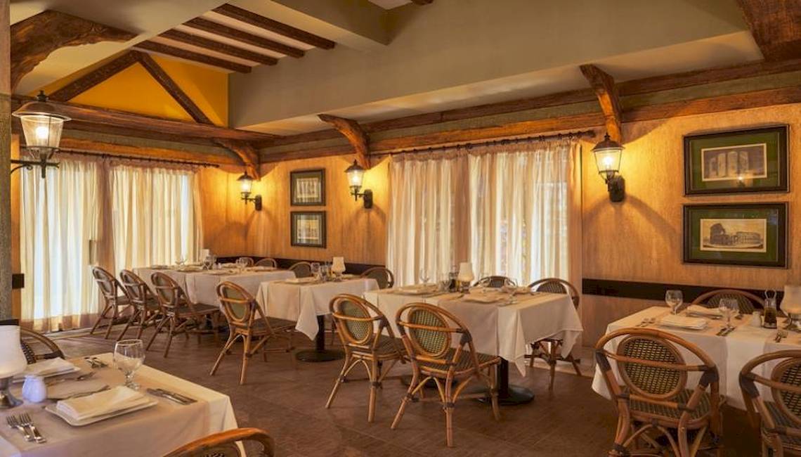 Innenansicht des Restaurants im Jaz Dar El Madina Hotel mit gedeckten Tischen, Stühlen und dekorativen Wandbildern.
