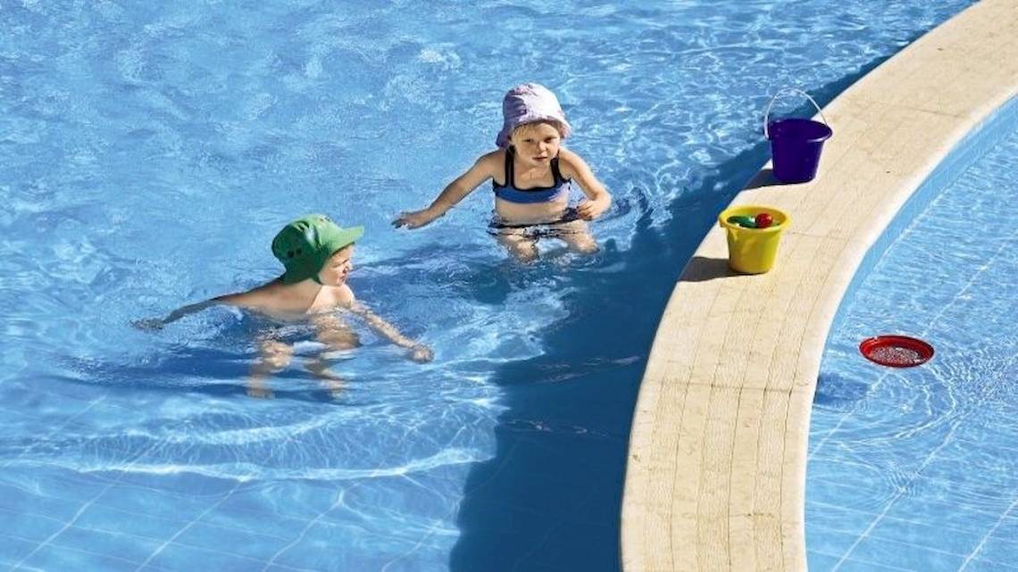 Zwei Kinder schwimmen im Pool des Jaz Dar El Madina Hotels, eines mit Hut und einer mit einem Eimer.