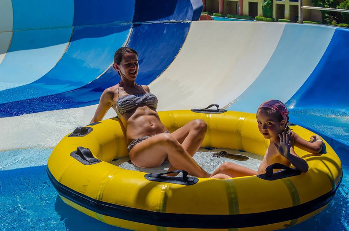 Zwei Frauen sitzen in einer gelben Schwimmring auf einer Wasserrutsche im Titanic Palace.