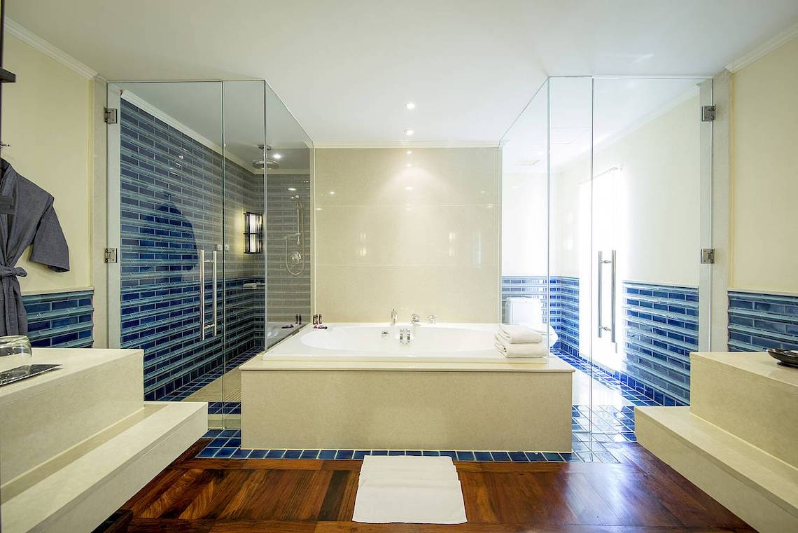 Badezimmer im Robinson Khao Lak Hotel mit Badewanne und blauen Fliesen.