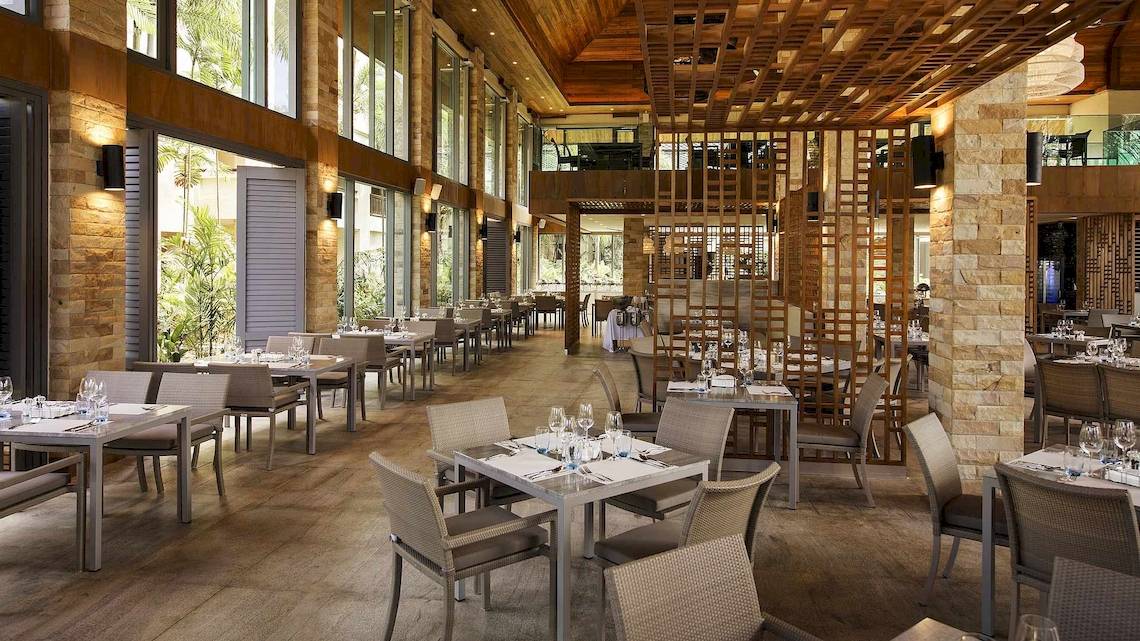 Innenansicht des Restaurants im Robinson Khao Lak Hotel mit runden Tischen und Stühlen.