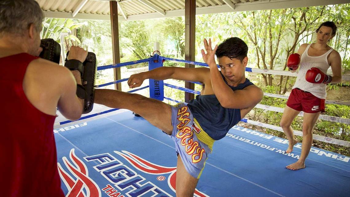 Muay-Thai-Training im Robinson Khao Lak mit zwei Männern im Ring und einem Mann, der einen Tritt ausführt.