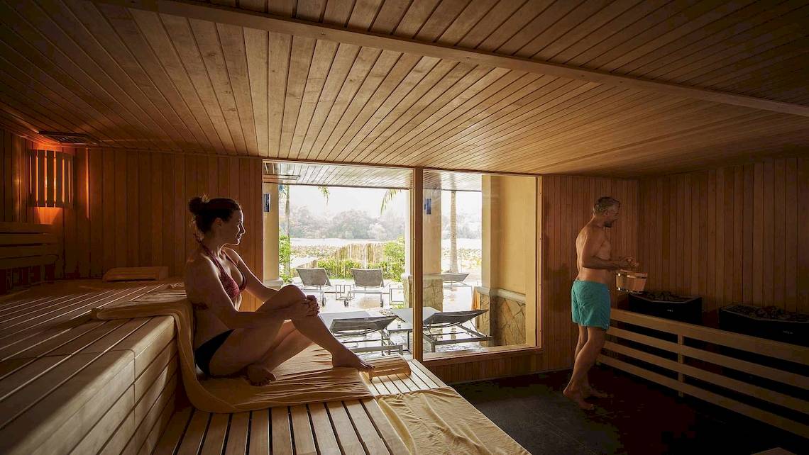 Eine Frau sitzt in der Sauna des Robinson Khao Lak Hotels, während ein Mann daneben steht.