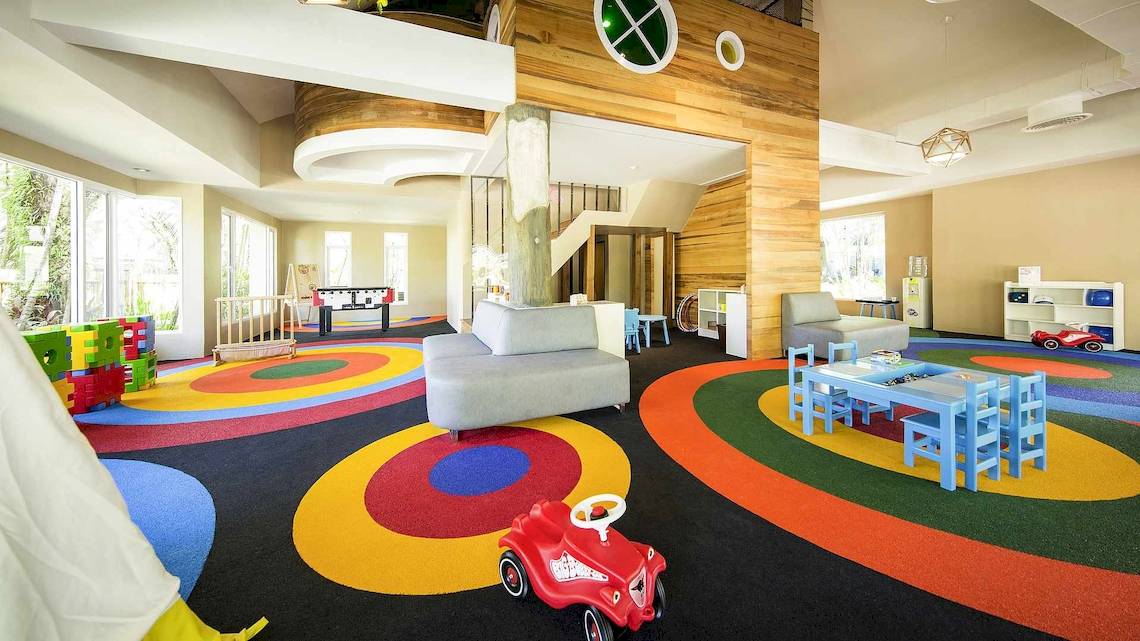 Das Kinderspielzimmer im Robinson Khao Lak Hotel mit bunten Teppichkreisen, Spielzeugautos und Spieltischen.