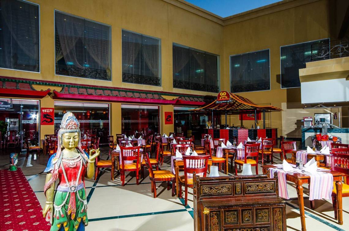 Innenansicht des Restaurants mit roten Sesseln und Buddha-Statue.