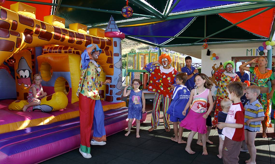 Kinder und Clowns spielen auf einer Hüpfburg im Freien im Grand Hotel Holiday Resort