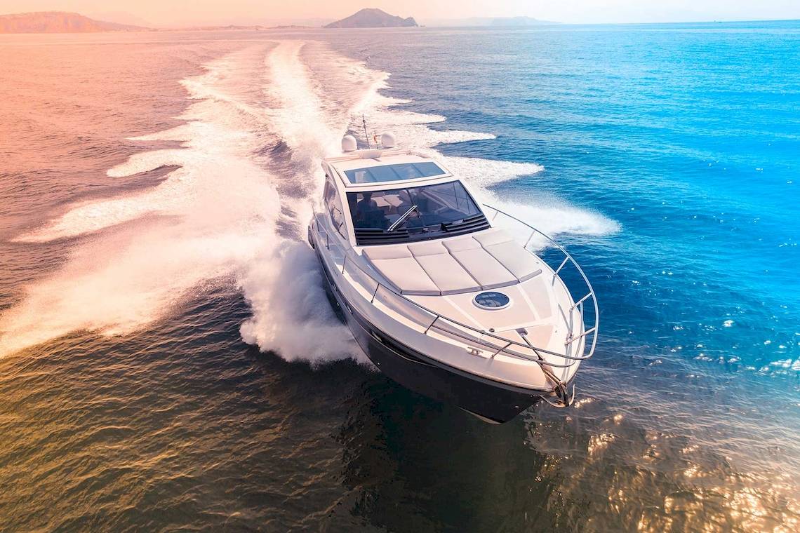 Ein Luxusboot fährt im Meer bei Sonnenuntergang und hinterlässt eine Welle