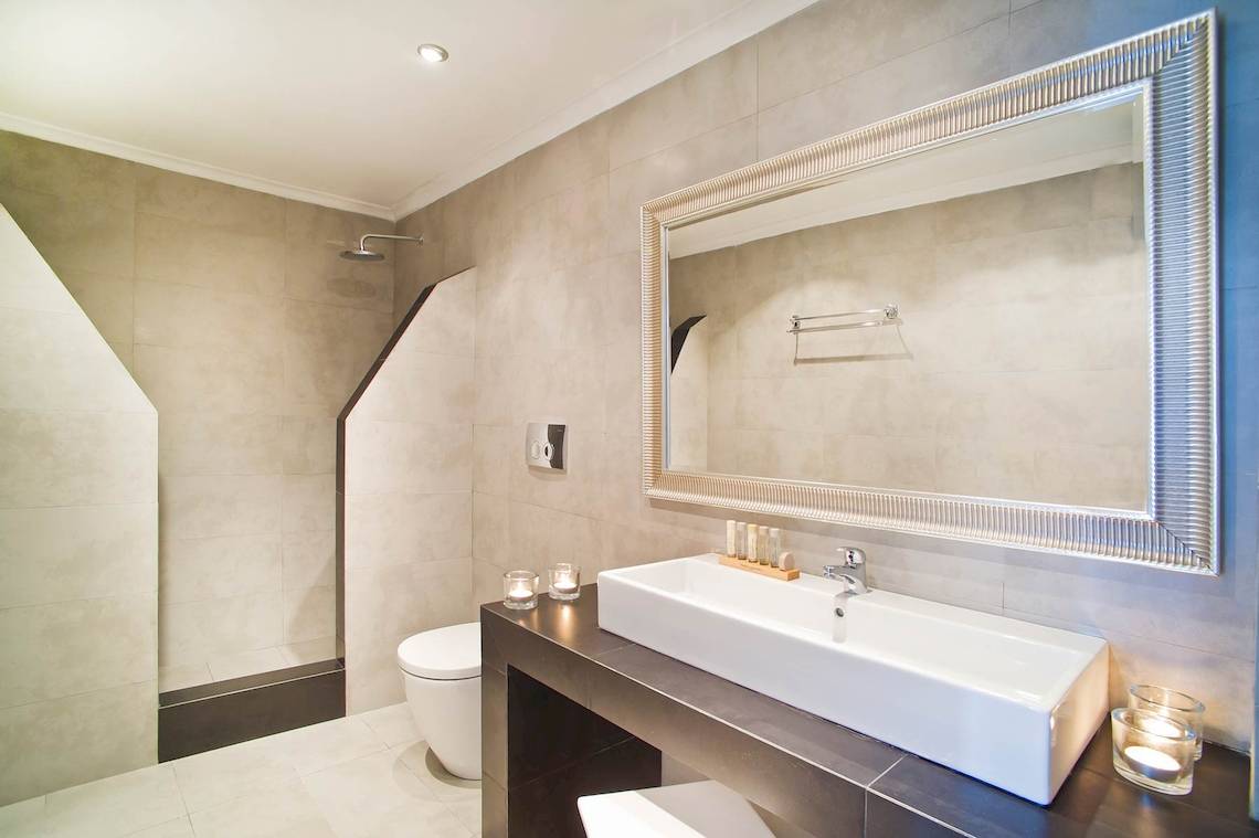 Badezimmer von Agali Houses mit weißem Waschbecken und silbernem Spiegel.