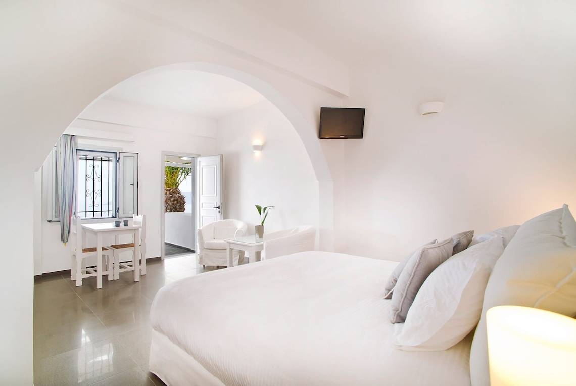 Schlafzimmer im Agali Houses mit Doppelbett, Sitzecke und Tisch, Fenster und Fernseher.