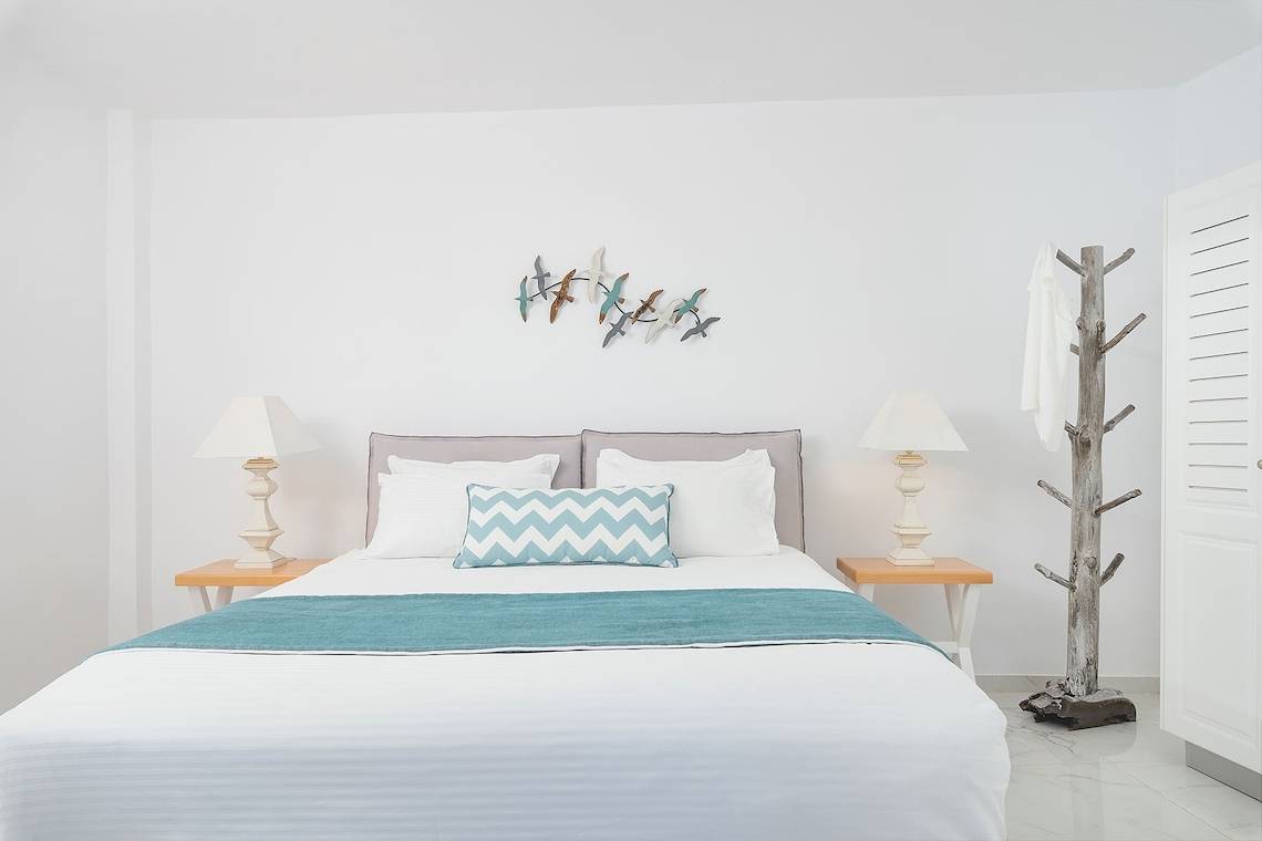 Schlafzimmer mit Bett, Lampen und Vogel Wandkunst in Agali Houses