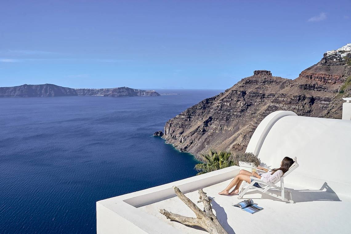 Frau auf dem Balkon von Agali Houses mit Aussicht auf das Meer