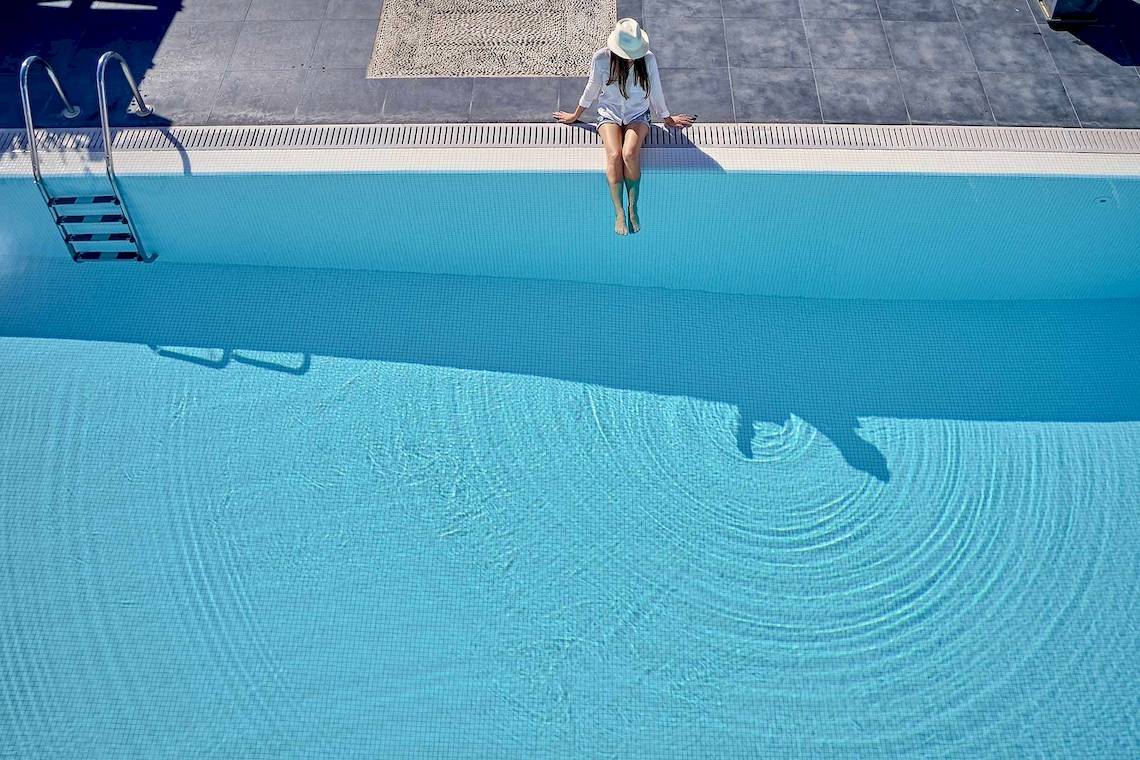 Eine Frau springt von der Poolkante in das Schwimmbad des Agali Houses Hotels.