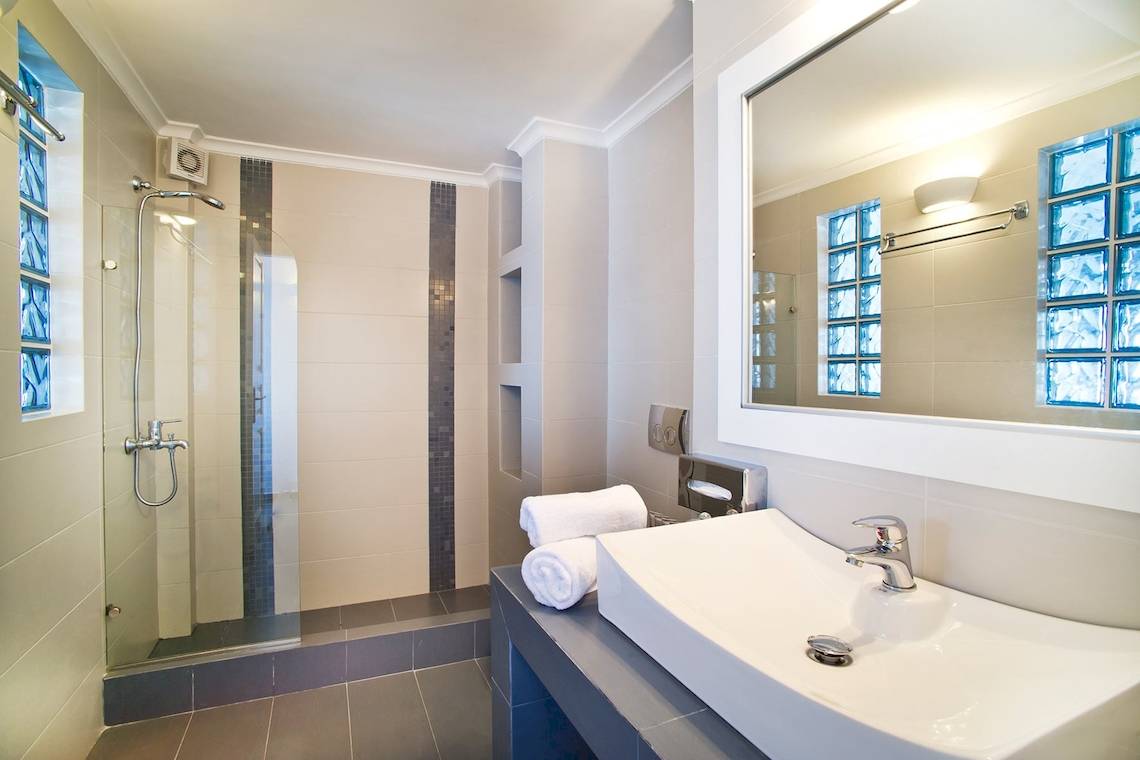 Badezimmer von Agali Houses mit Dusche, Waschbecken und Spiegel.