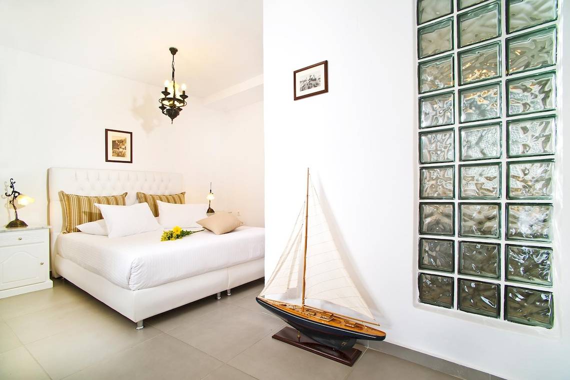 Schlafzimmer im Agali Houses Hotel mit einem großen Bett, Modellboot und modernen Wanddesigns.