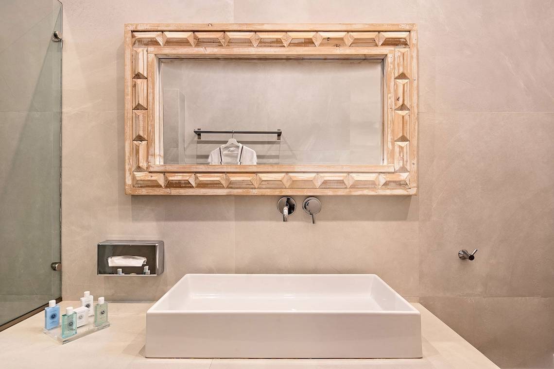 Badezimmer im Agali Houses Hotel mit zeitgenössischem Design, einem weißen Waschbecken und einem gerahmten Spiegel.