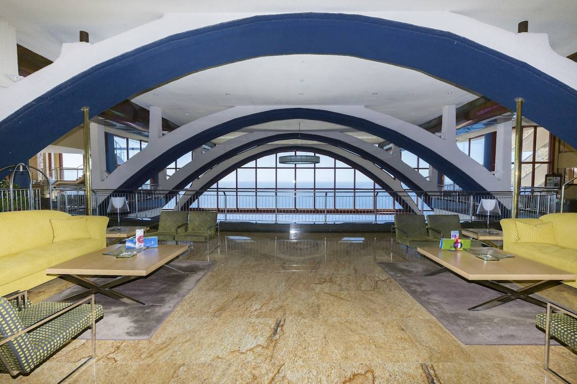 Hotellobby mit gelben Sofas und Meerblick durch große Glasfenster