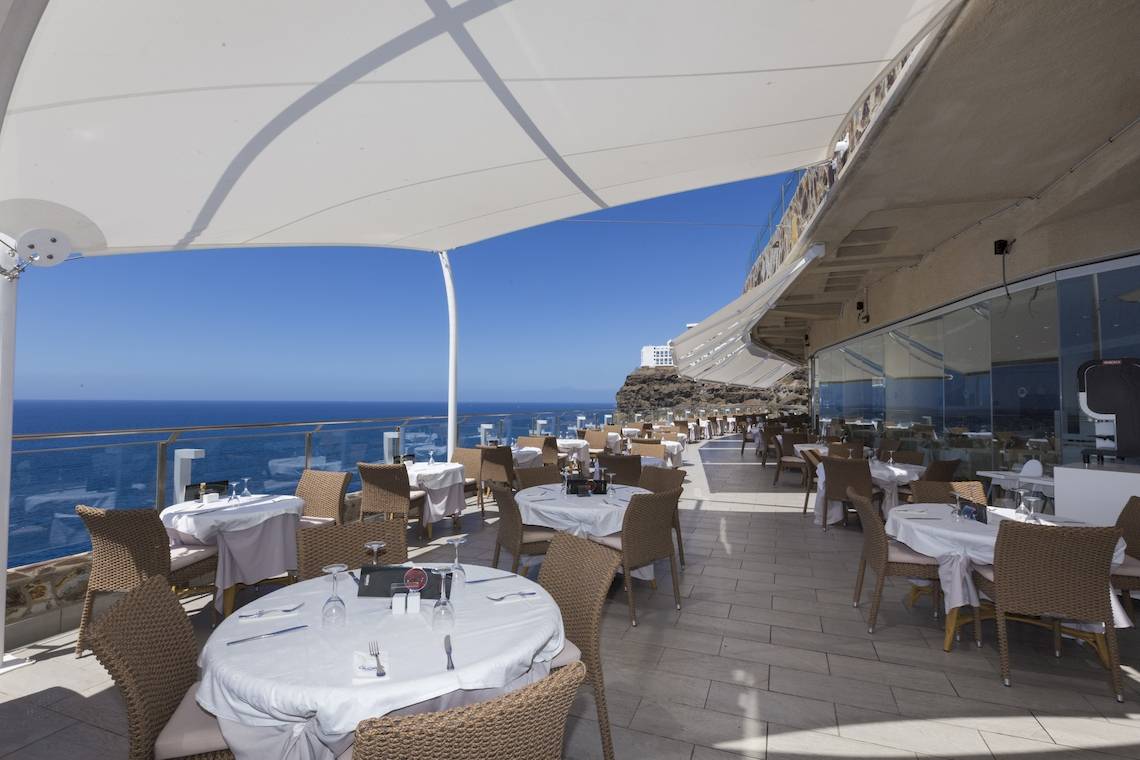 Hoteldachterrasse mit Blick auf das Meer, gedeckte Tische und Stühle.