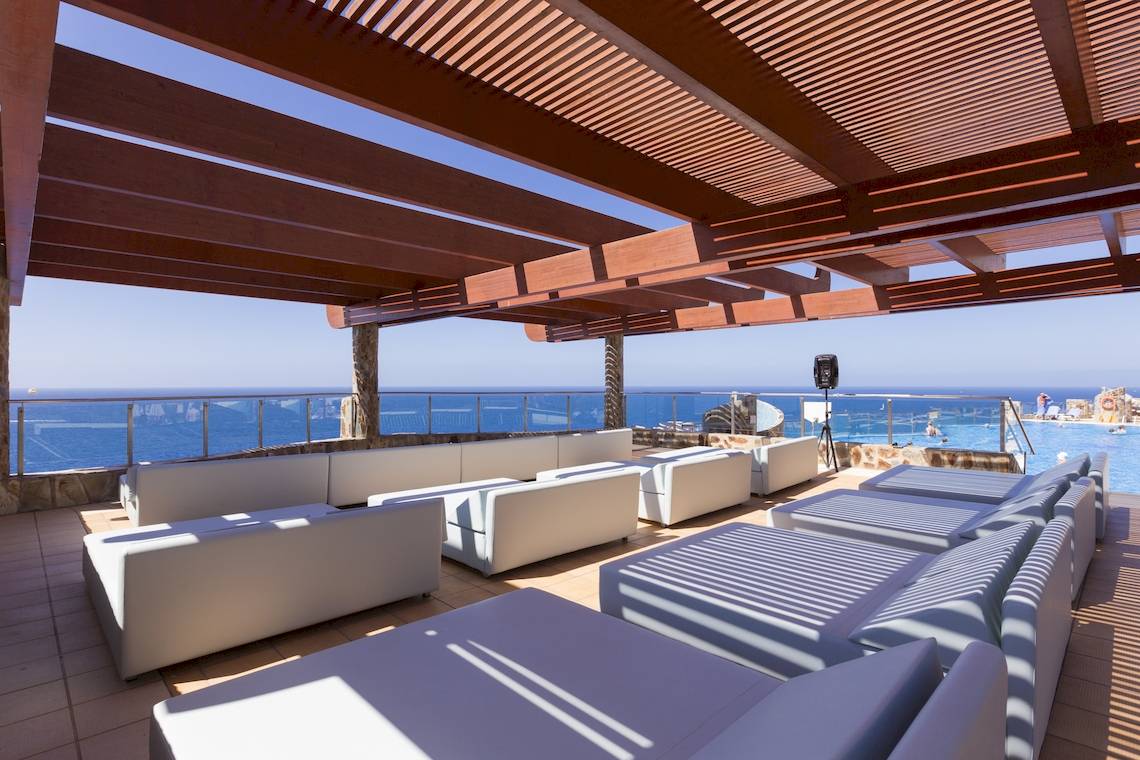 Dachterrasse des Gloria Palace Amadores Thalasso & Hotel mit weißen Lounge-Sofas und Meerblick.