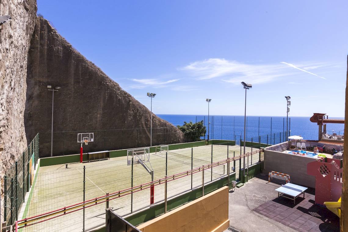 Außensportplatz mit Blick auf das Meer und einer Poolanlage.