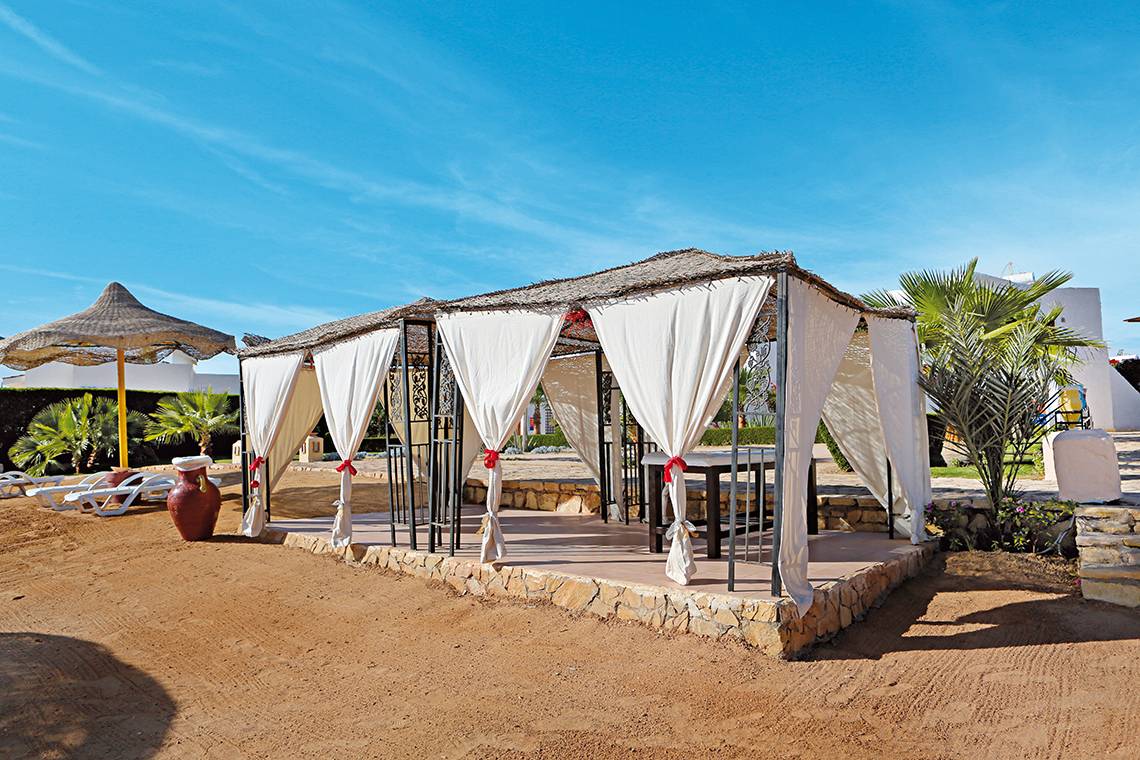 Außenbereich des Sharm Club Beach Resort mit Pavillon und Sonnenschirm