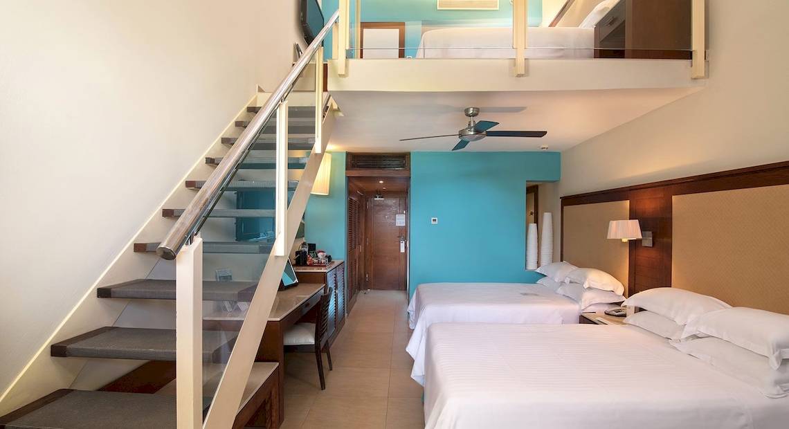 Hotelzimmer im Barcelo Bavaro Palace mit zwei Betten und einer Zwischenebene.