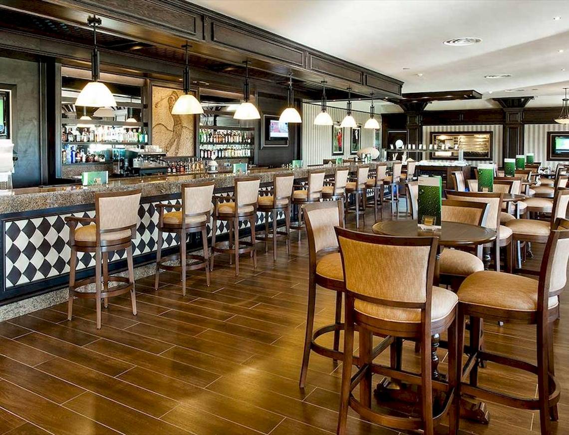 Innenansicht der Bar des Barcelo Bavaro Palace Hotels mit Holzboden und Stühlen.