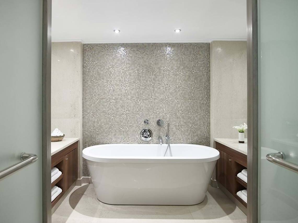 Ein Badezimmer mit einer freistehenden Badewanne und einer Mosaikwand.