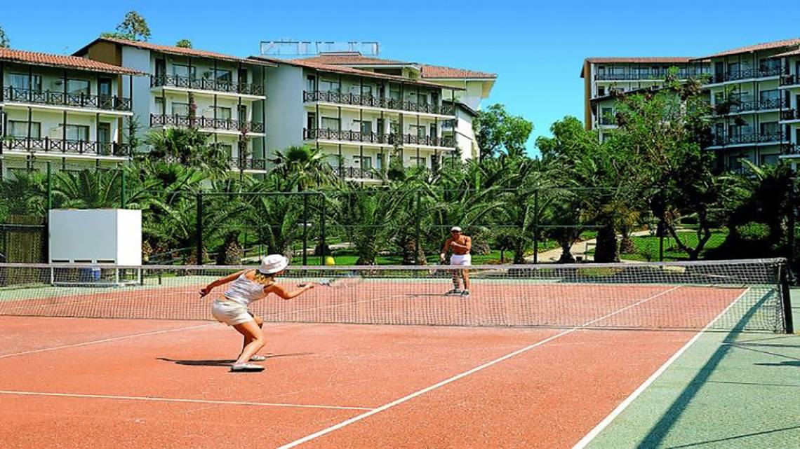 Tennisplatz im Sealife Buket Resort & Spa mit zwei Spielern und einem Gebäude im Hintergrund.