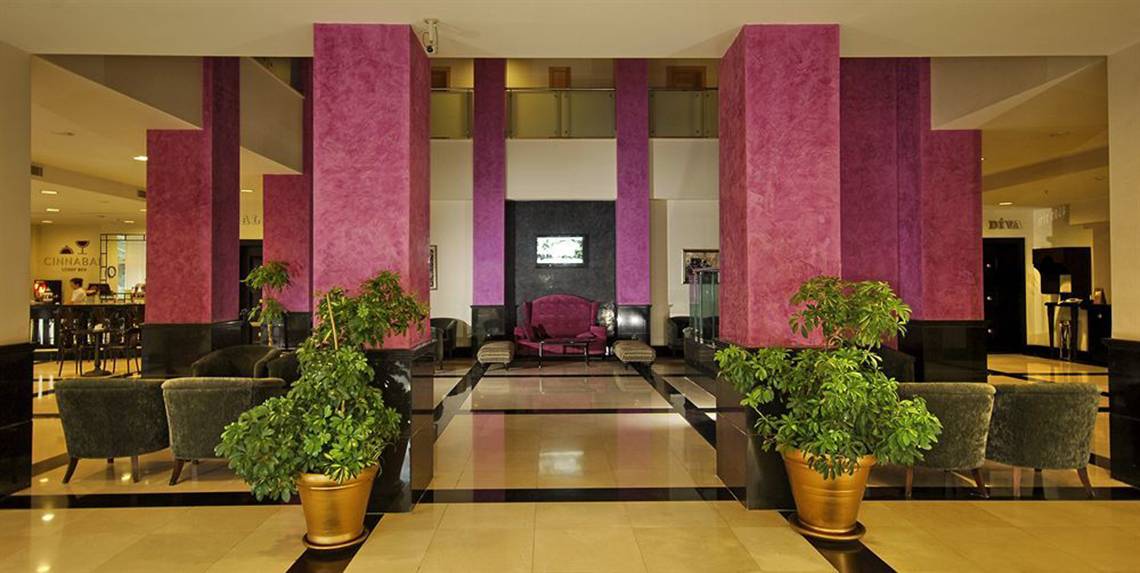 Lobby des Sealife Buket Resort & Spa mit hohen pinken Säulen und grünen Pflanzen in goldenen Töpfen.