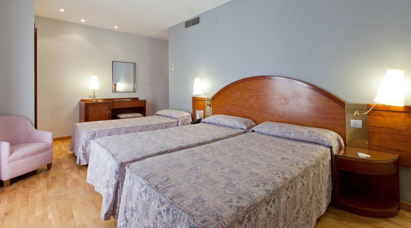 Doppelzimmer im Gargallo Rialto Hotel mit zwei Betten, Nachttischen und einem rosa Stuhl.
