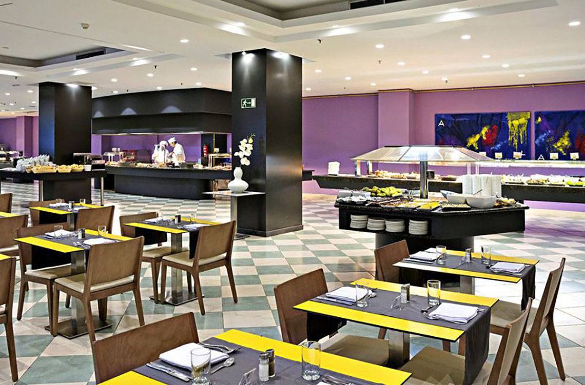 Innenansicht des Restaurants im Gran Canaria Princess Hotel mit geometrischem Boden, gepolsterten Stühlen und Tischen sowie Buffets.