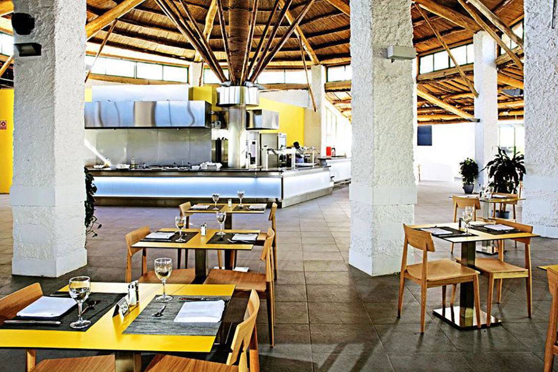 Innenansicht des Restaurants im Gran Canaria Princess Hotel mit gelben Tischen und Holzstühlen.