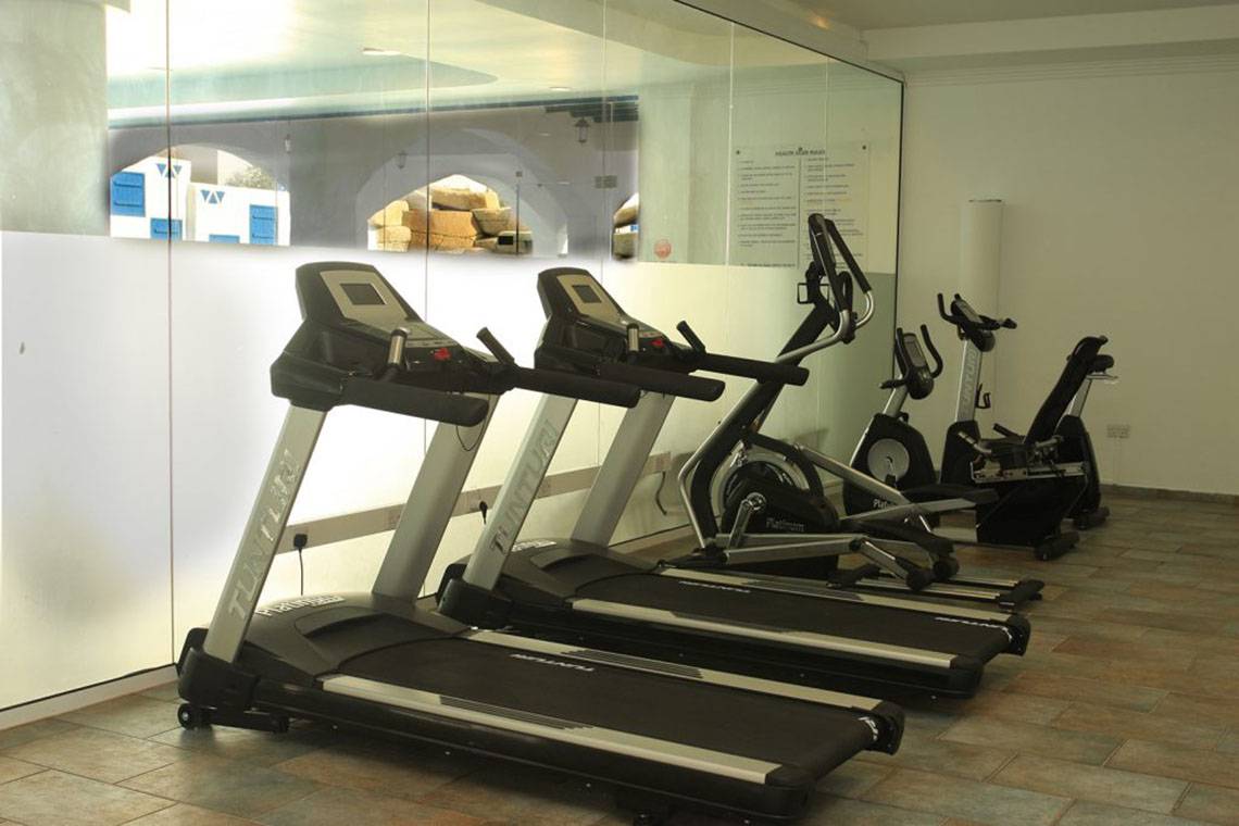 Fitnessraum im Callisto Holiday Village mit mehreren Laufbändern und anderen Geräten.