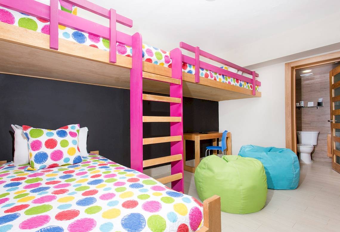 Ein Kinderzimmer mit bunten Etagenbetten, bunten Kissen und zwei farbigen Sitzsäcken.
