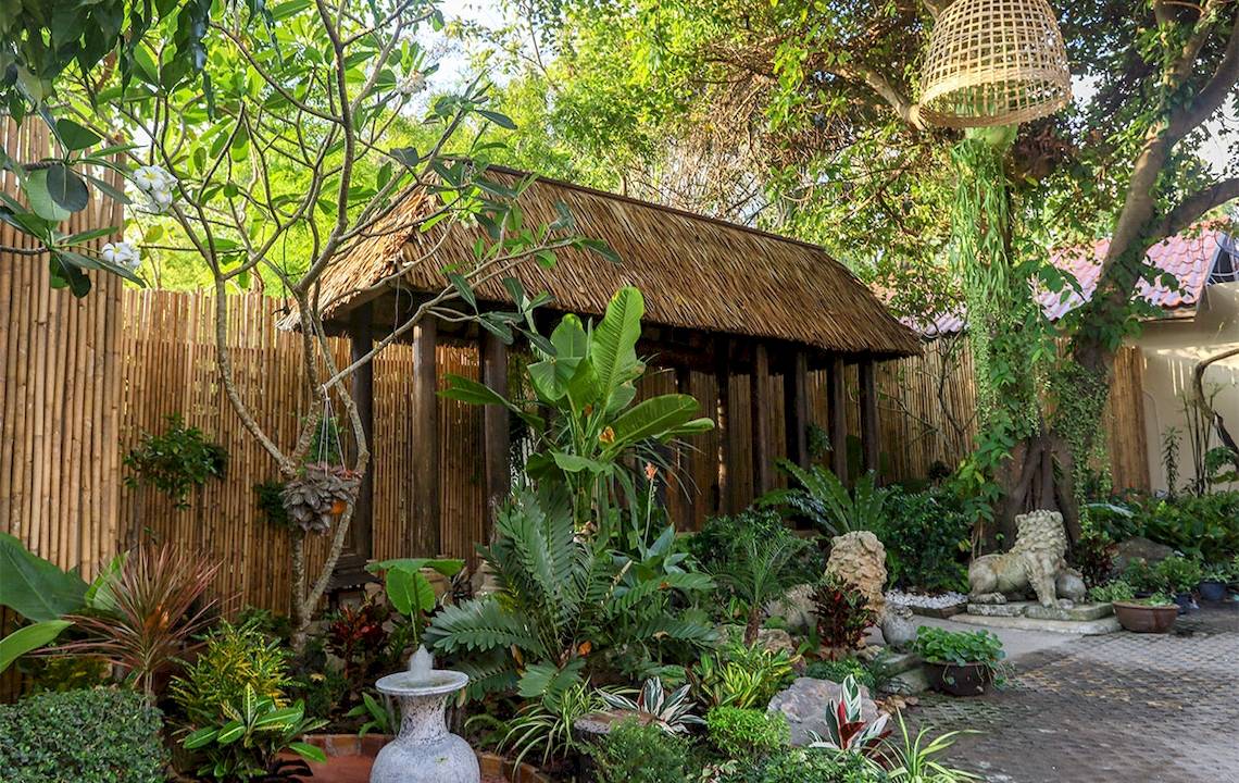 Tropischer Garten im Saree Samui Resort mit einer kleinen strohgedeckten Hütte.