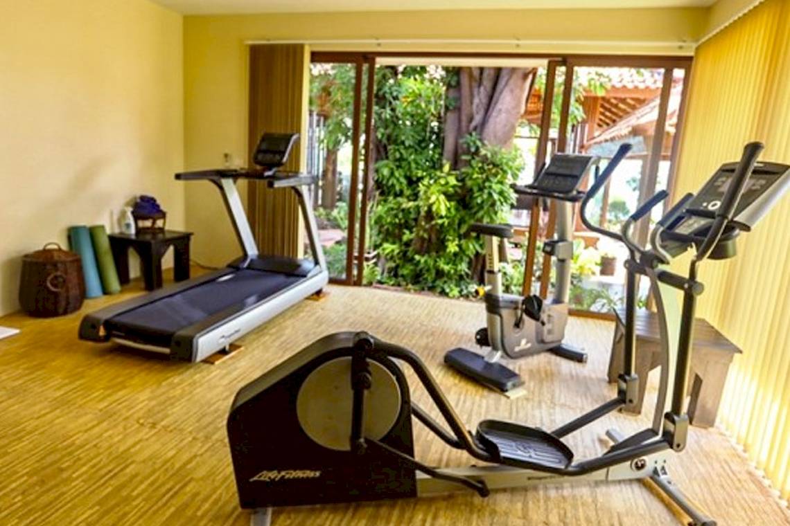 Fitnessbereich im Saree Samui Resort mit Geräten und Blick auf den Garten.