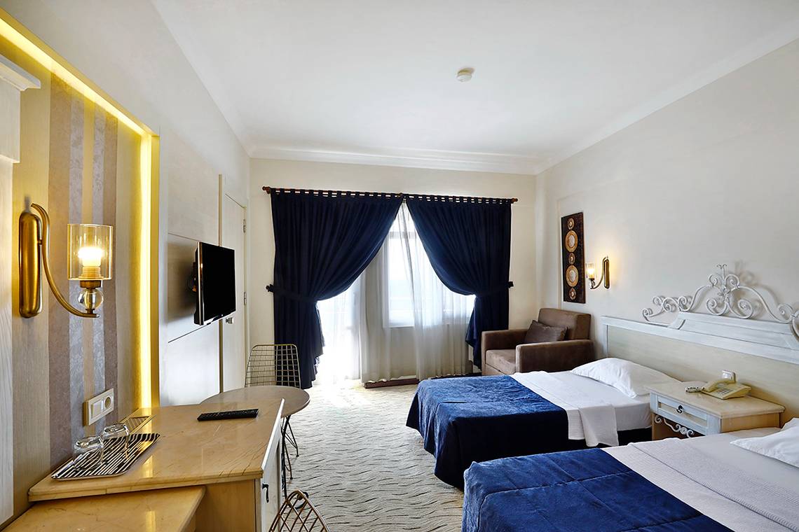 Doppelzimmer im Club Yali Hotels & Resort mit zwei Betten, Fernseher und einem Schreibtisch.